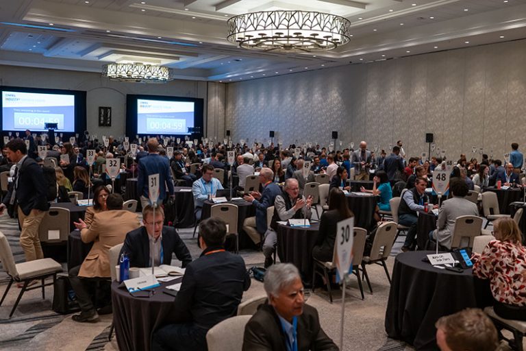 IGF-2025 Hundreds of people sit at small tables in one-on-one meetings in a large ballroom.