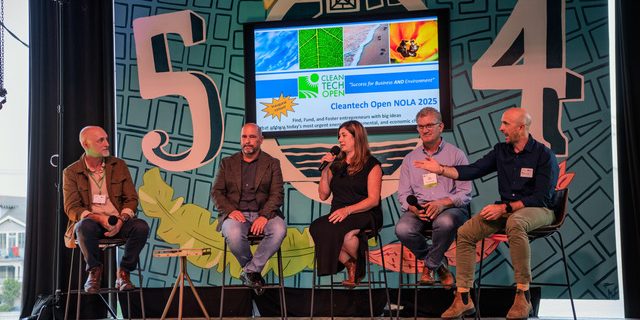 At an event, five people sit on stools during a panel discussion.