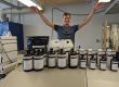 Evan raises his arms, palms down, over a collection of containers with the name, “Zila Bioworks” written on them.